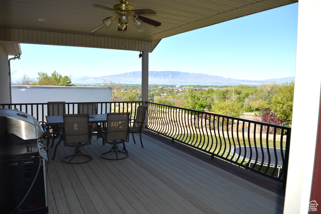 Wooden terrace with a ceiling fan, a mountain view, outdoor dining area, and area for grilling