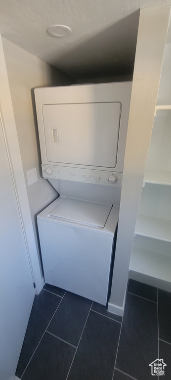 Laundry room featuring estacked washer and dryer and dark tile patterned floors