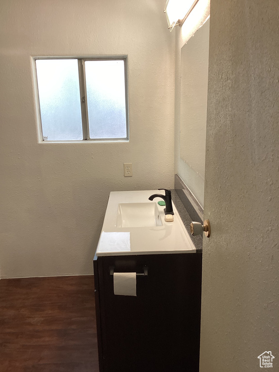 Bathroom featuring a textured wall, vanity, and wood finished floors