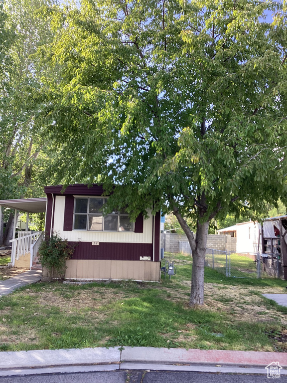 Manufactured / mobile home featuring a carport, a front yard, and fence