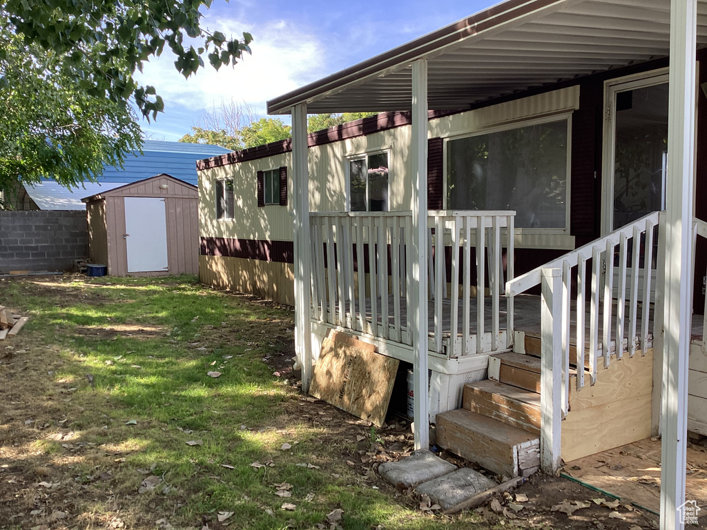 Exterior space featuring a yard, fence, a storage unit, and an outbuilding