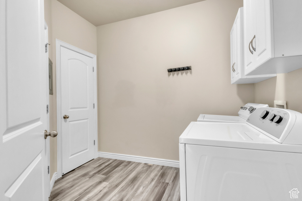 Laundry room featuring cabinet space, washer and dryer, light wood-style floors, and baseboards