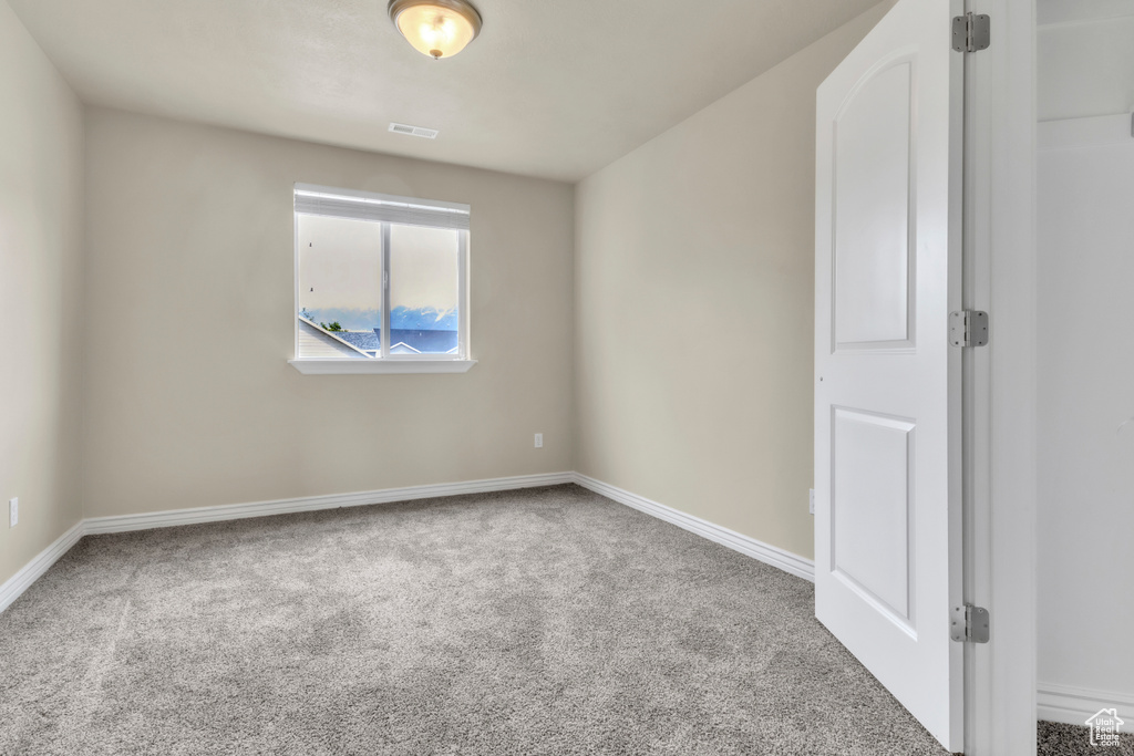 Spare room featuring carpet flooring and baseboards