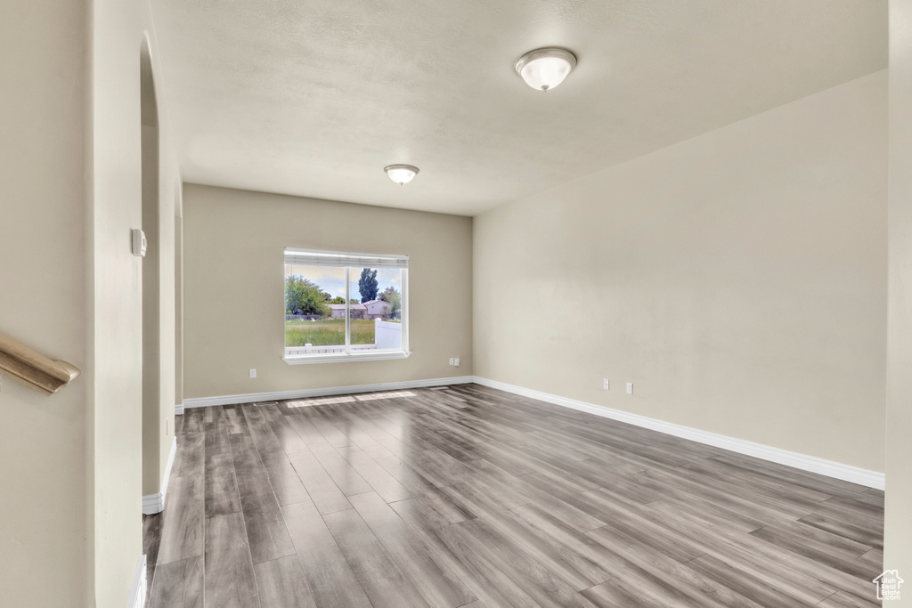Empty room with wood finished floors, baseboards, and arched walkways
