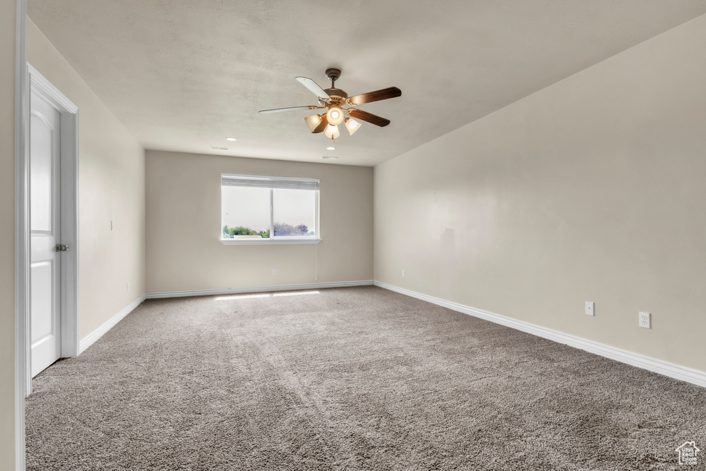 Carpeted empty room with a ceiling fan and baseboards