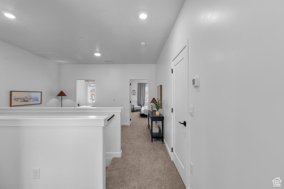 Corridor with recessed lighting, light colored carpet, visible vents, and an upstairs landing