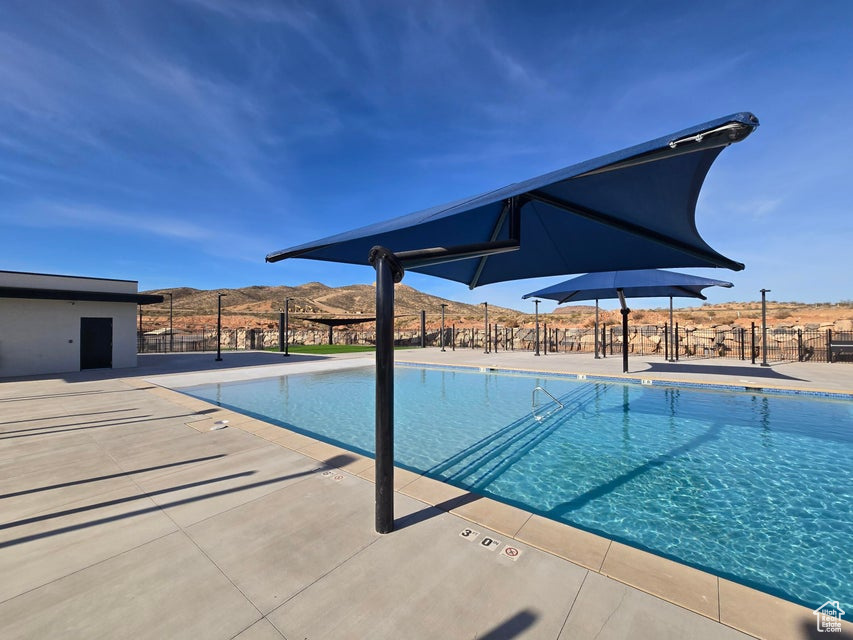 Pool with fence, a mountain view, and a patio