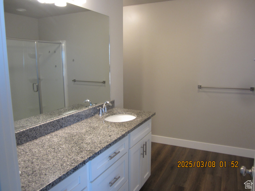 Full bath with a shower stall, baseboards, wood finished floors, and vanity