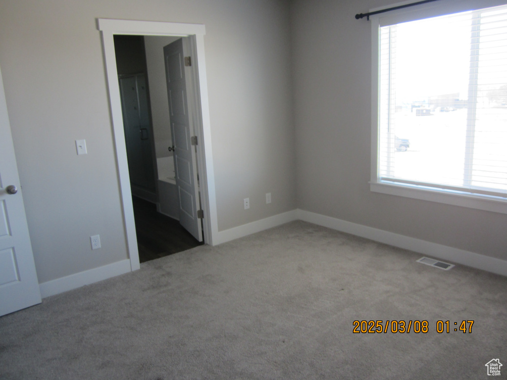 Carpeted empty room with baseboards and visible vents