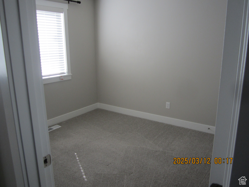 Carpeted empty room with visible vents and baseboards