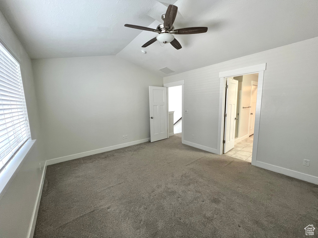 Unfurnished bedroom featuring multiple windows, baseboards, vaulted ceiling, and carpet flooring