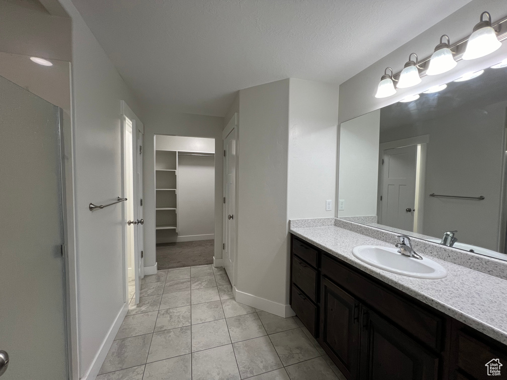 Bathroom with tile patterned flooring, vanity, baseboards, and a spacious closet