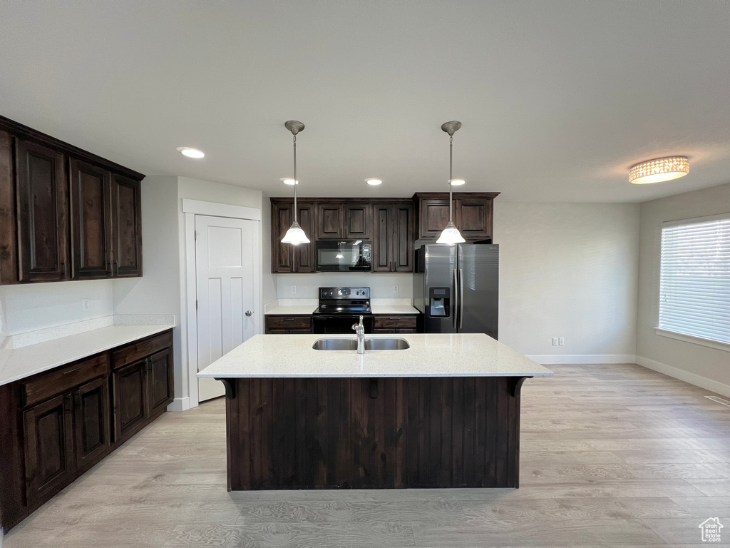 Kitchen featuring black microwave, range with electric cooktop, a sink, dark brown cabinets, and stainless steel fridge