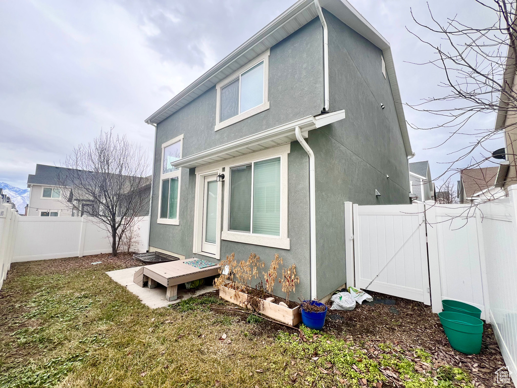 Back of house featuring a gate, a fenced backyard, and stucco siding