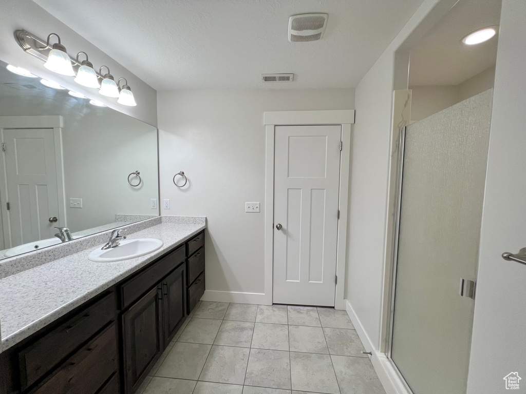 Full bath featuring visible vents, a stall shower, vanity, tile patterned flooring, and baseboards