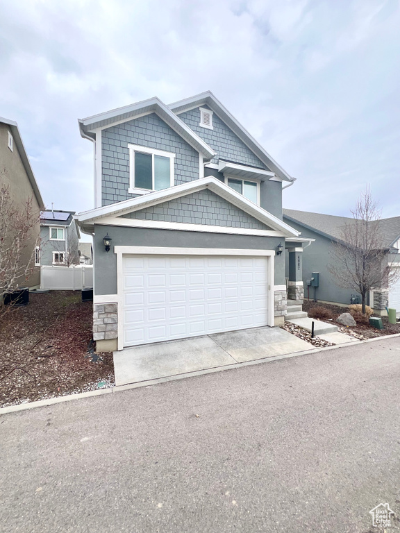 View of front of home featuring a garage, stone siding, concrete driveway, and stucco siding