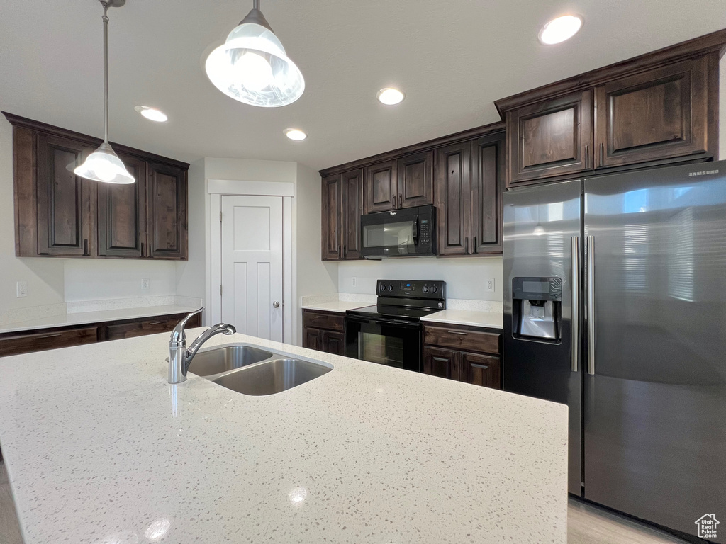 Kitchen with black appliances, dark brown cabinets, and a sink