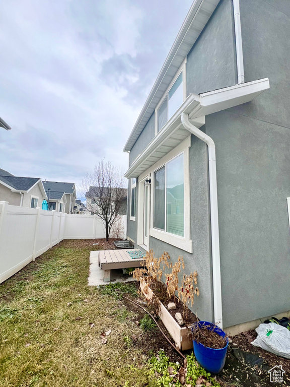 View of property exterior featuring fence private yard, a yard, a deck, and stucco siding