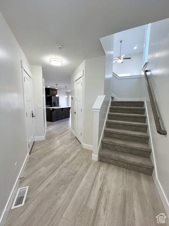 Staircase featuring a ceiling fan, visible vents, baseboards, and wood finished floors