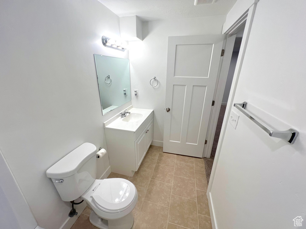 Half bathroom featuring baseboards, vanity, toilet, and tile patterned floors