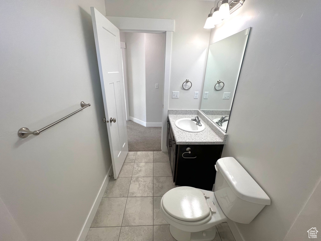 Half bathroom featuring toilet, baseboards, and vanity