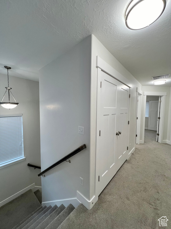 Staircase featuring baseboards, carpet flooring, visible vents, and a textured ceiling