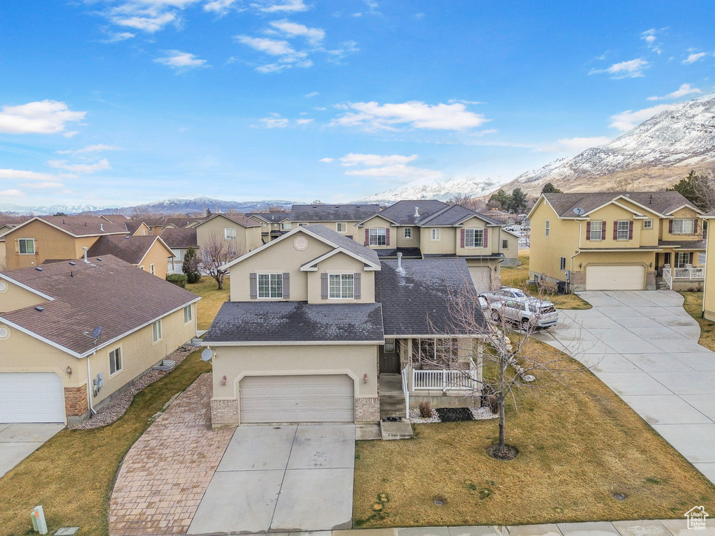 Traditional-style home featuring stucco siding, a front yard, a mountain view, a residential view, and driveway