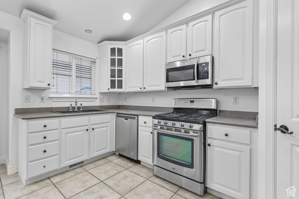 Kitchen with visible vents, white cabinets, dark countertops, appliances with stainless steel finishes, and a sink