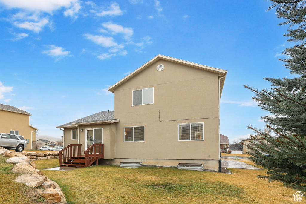 Rear view of house with a lawn and stucco siding