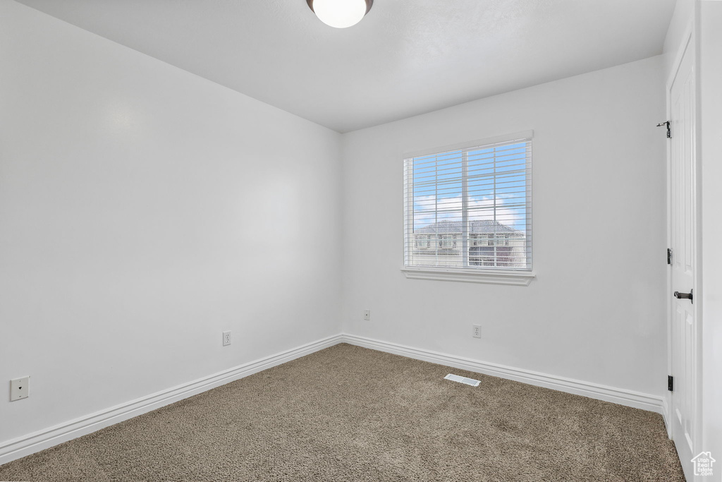 Carpeted spare room featuring visible vents and baseboards