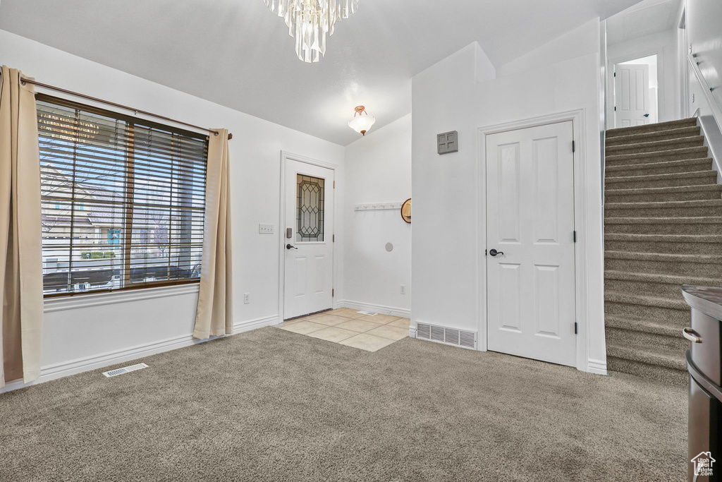 Foyer with stairway, lofted ceiling, light colored carpet, and visible vents