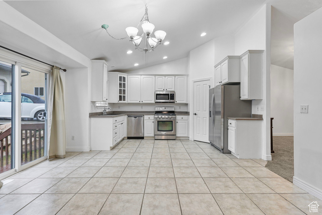 Kitchen featuring lofted ceiling, a chandelier, light tile patterned flooring, appliances with stainless steel finishes, and dark countertops