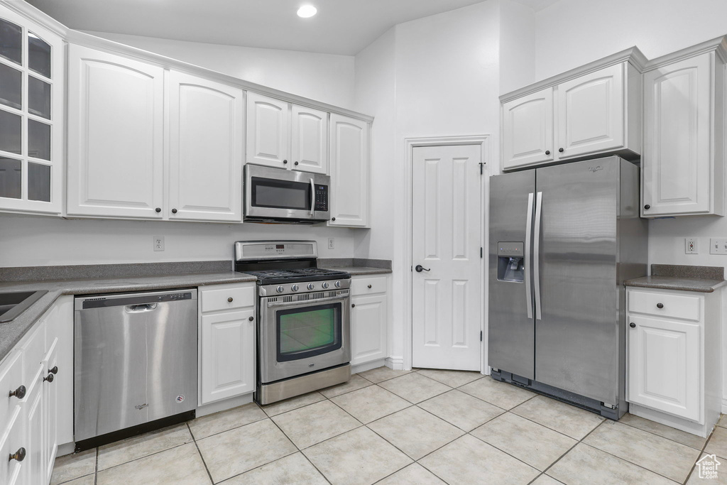 Kitchen with appliances with stainless steel finishes, dark countertops, and light tile patterned floors