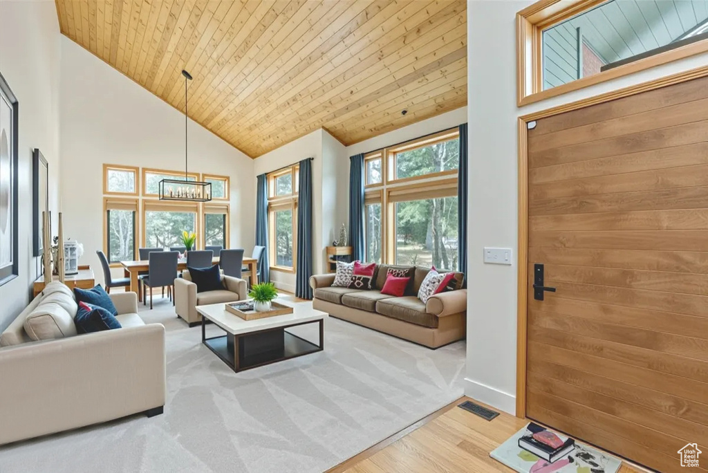 Living area with wood finished floors, high vaulted ceiling, wooden ceiling, and a chandelier