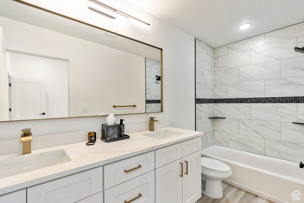 Bathroom featuring double vanity, wood finished floors, a sink, and toilet