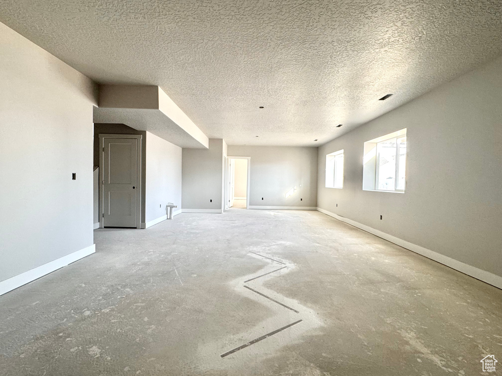 Unfurnished room featuring a textured ceiling and baseboards
