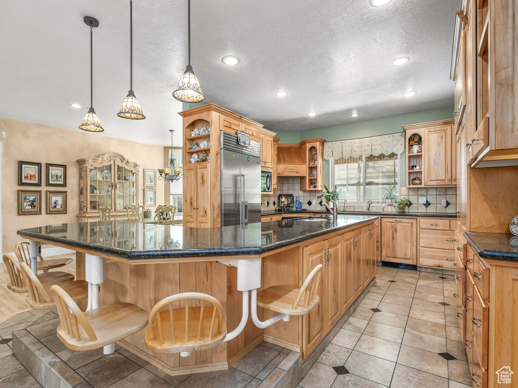 Kitchen with open shelves, built in refrigerator, tasteful backsplash, a sink, and a textured ceiling