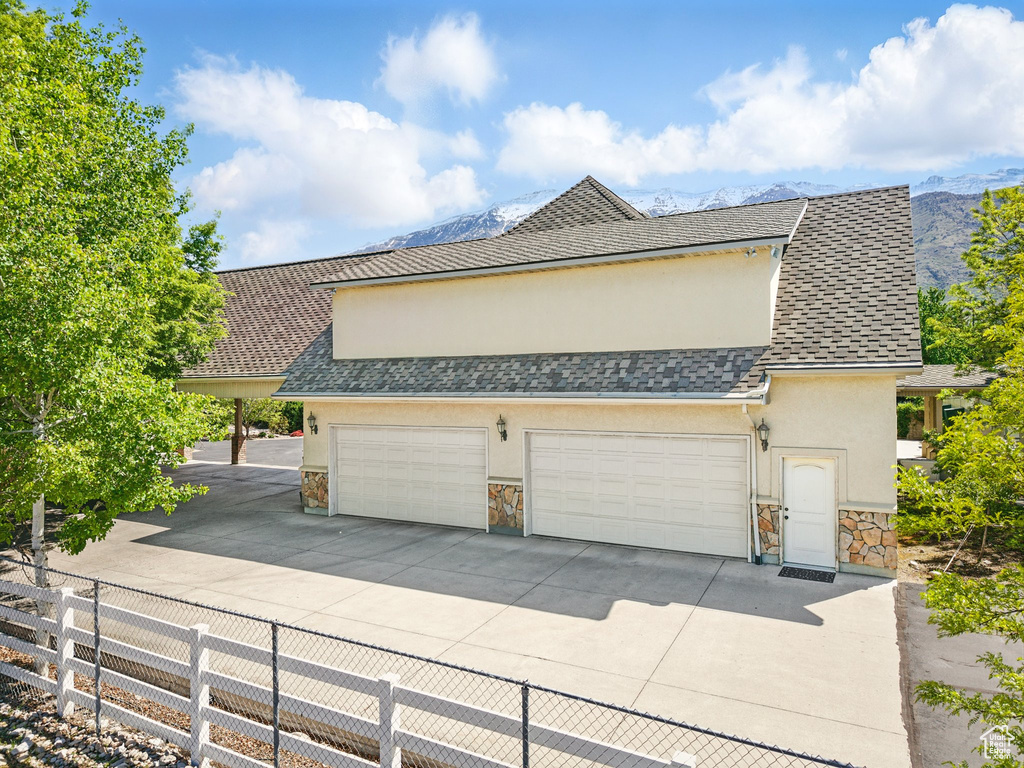 View of front facade with stucco siding, stone siding, fence, and driveway