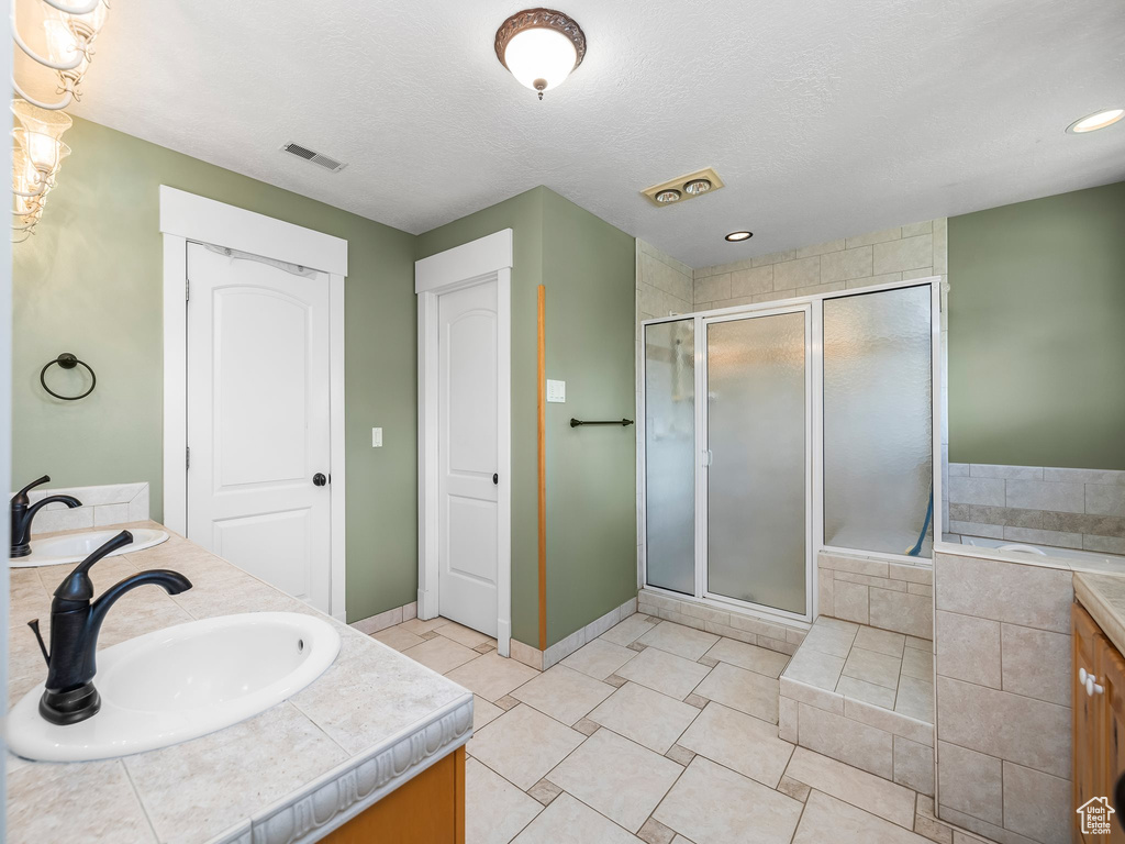 Bathroom with double vanity, a shower stall, tile patterned flooring, baseboards, and a bath
