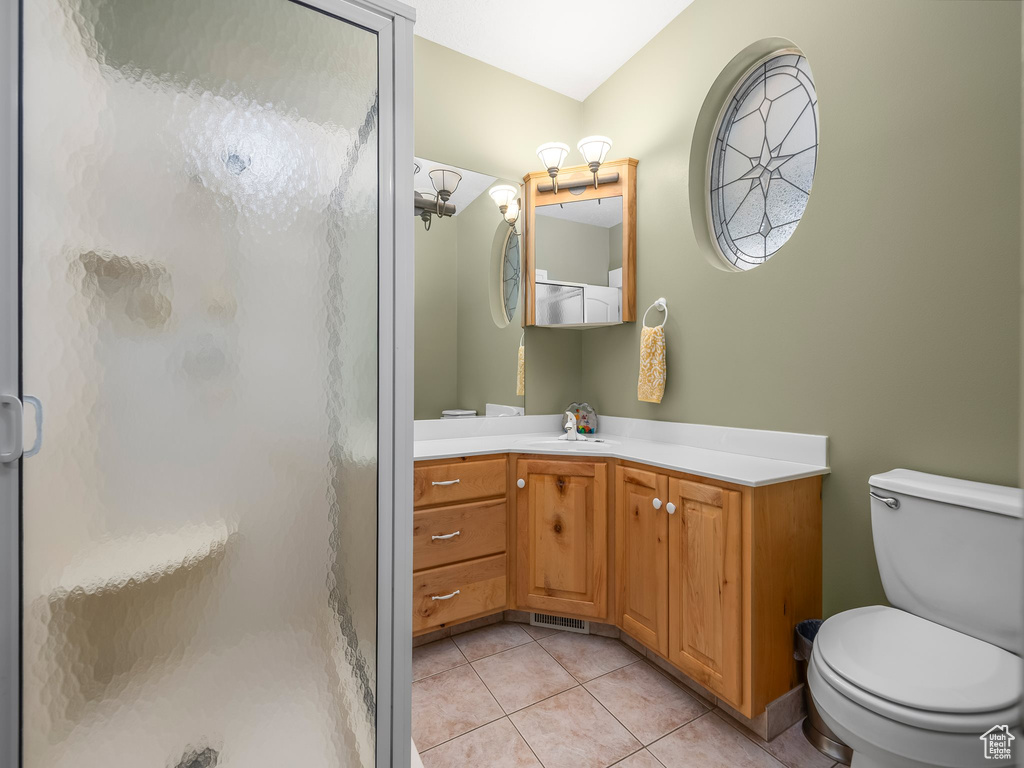 Bathroom featuring toilet, a stall shower, tile patterned floors, and vanity