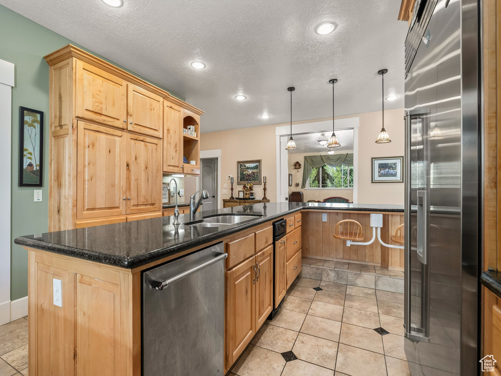Kitchen with appliances with stainless steel finishes, a sink, a center island with sink, recessed lighting, and light brown cabinetry