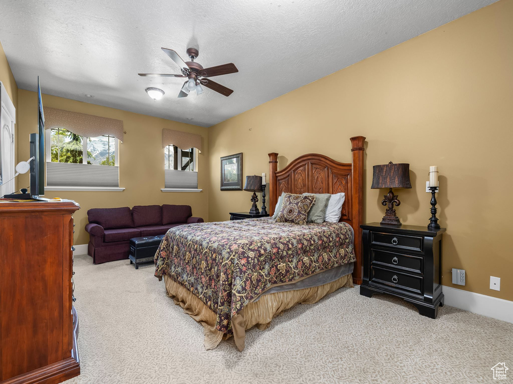 Carpeted bedroom with a ceiling fan, baseboards, and a textured ceiling
