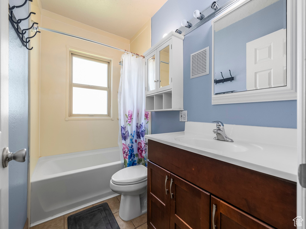 Full bath with toilet, tile patterned flooring, vanity, and shower / bath combo