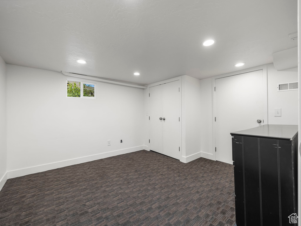 Basement with dark carpet, recessed lighting, and baseboards