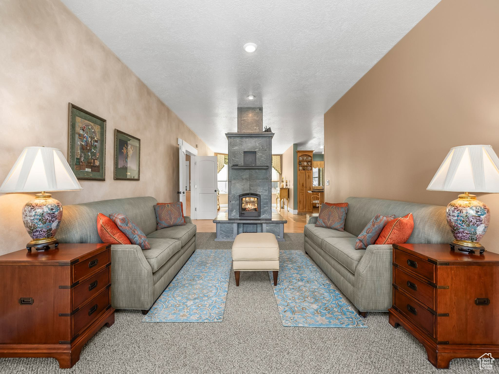 Living area with light colored carpet, a tiled fireplace, and a textured ceiling