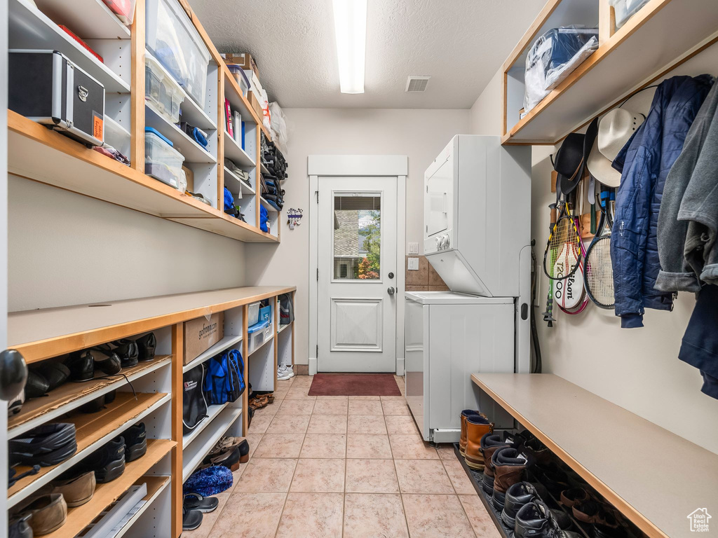 Clothes washing area featuring stacked washer and clothes dryer and a textured ceiling