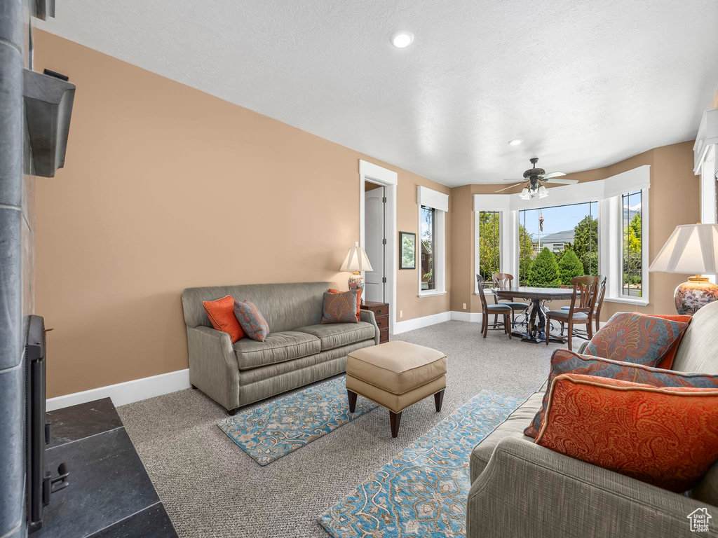 Carpeted living area featuring ceiling fan, baseboards, and recessed lighting