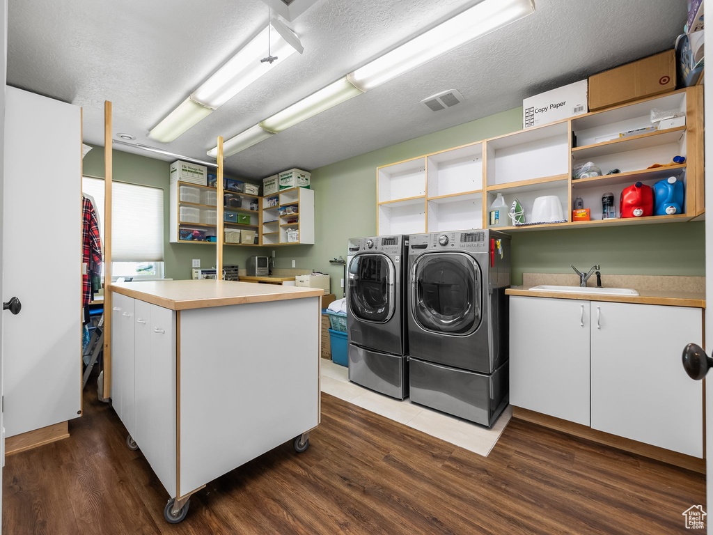 Washroom with washer and dryer, dark wood-type flooring, cabinet space, and a textured ceiling