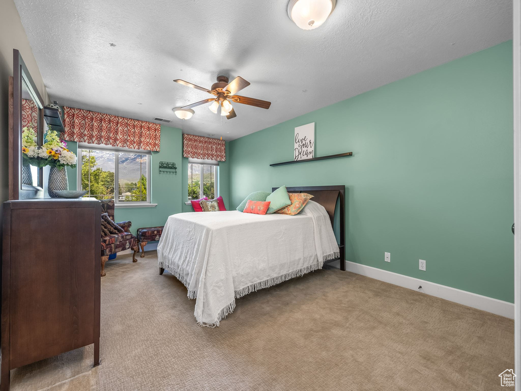 Bedroom with carpet floors, baseboards, a textured ceiling, and a ceiling fan