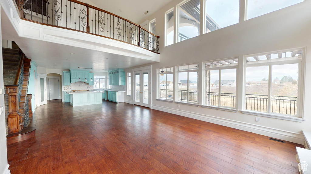 Unfurnished living room featuring stairway, visible vents, dark wood finished floors, and arched walkways